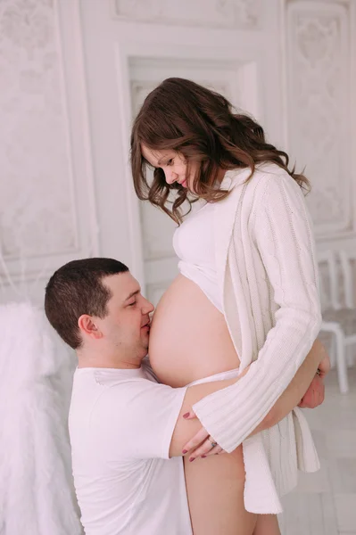 Сім'я чекає народження дитини. Вагітна жінка та її чоловік носять білий одяг — стокове фото