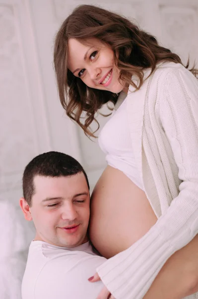 Familia esperando el nacimiento del bebé. Una mujer embarazada y su marido con ropa blanca — Foto de Stock