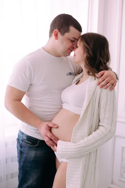 Família à espera do nascimento do bebé. Uma mulher grávida e seu marido vestindo roupas brancas — Fotografia de Stock
