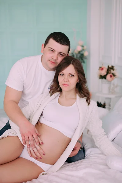 家族は、赤ちゃんの誕生を待っています。妊娠中の女性と彼女の夫の身に着けている白い衣類 — ストック写真