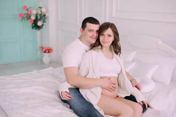 Семья ждет рождения ребенка. Беременная женщина и ее муж в белой одежде — стоковое фото