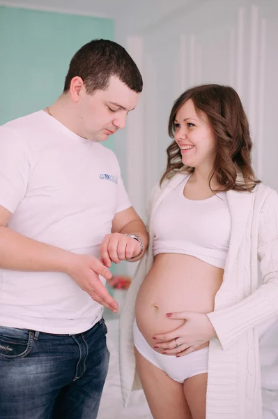 Familia esperando el nacimiento del bebé. Una mujer embarazada y su marido con ropa blanca — Foto de Stock