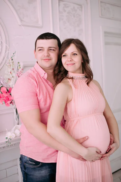 Familia esperando el nacimiento del bebé. Una mujer embarazada y su marido con ropa blanca — Foto de Stock