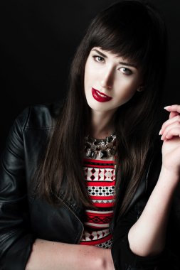 Bir deri ceket ve kırmızı desen elbise giyen bir kadın