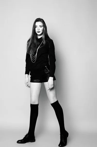 Chica joven en calcetines negros y pantalones cortos, sentado im blanco y negro — Foto de Stock