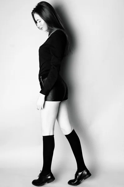 Gadis muda dengan kaus kaki hitam dan celana pendek, duduk hitam dan putih im — Stok Foto