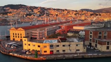 Güneş Genova 'nın panoramasını ve limanını sarı ve pembe renklerle boyadı. Kalkan geminin yüksek kısmından görüntüle.