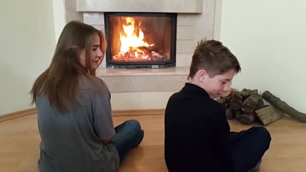 Adolescentes Sentados Chão Frente Lareira Observando Chamas Tentando Sentar Pequeno — Vídeo de Stock