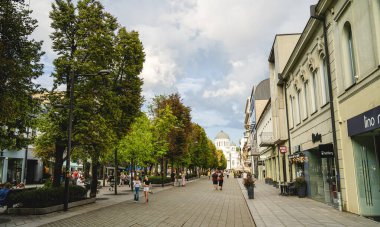 Kaunas 'ta ağaçlar arasında yürüyen insanlar. 