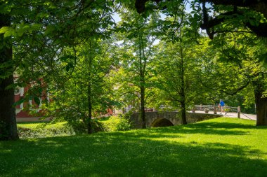 Lush green trees surrounding small stone bridge Riga
