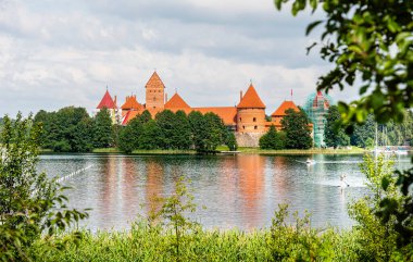 Trakai kalesi ağaçlarla çevrili göle yansıyor.