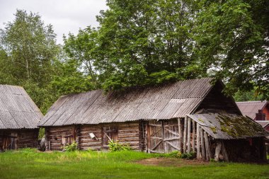 Old wooden barn surrounded by green trees in Lithuania
