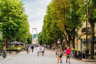 Kaunas 'ta ağaçlar arasında yürüyen insanlar.