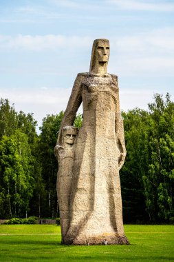 Salaspil 'deki büyük taş heykel yeşilliklerle çevrili.