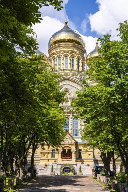 Yeşil ağaçlarla çevrili altın katedral kubbeleri Liepaja