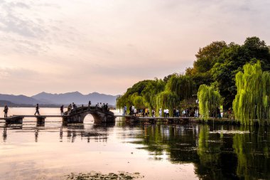 Batı Hangzhou Gölü 'nde insanlar köprüde yürüyor.