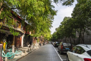 Xian Center 'da park etmiş arabalarla ağaçlarla kaplı bir cadde.