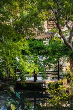 Suzhou Bahçesi 'nde geleneksel mimariyi çevreleyen gür yeşillik.