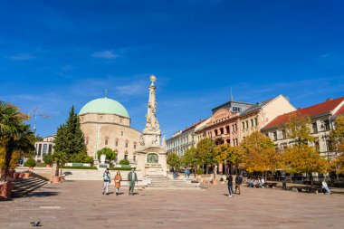 Pecs Meydanı 'nda tarihi binalarla yürüyen insanlar.