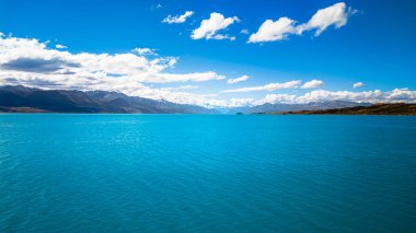 Açık mavi Pukaki Gölü parlak gökyüzünün altında