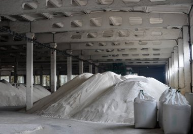Beyaz granüle edilmiş fosfat gübrelerini depolamak için bir depo. Yığınla büyük çantaya dolduruyorum..