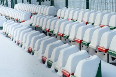 Kışın yoğun olarak kar kapaklarıyla kaplı açık stadyum koltukları. Seçici odak.