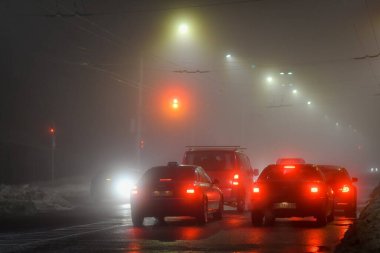 Şehirde trafik ışıkları olan sisli bir gece manzarası.