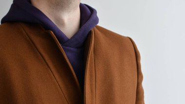 Erkek kıyafetleri, mor günlük kapüşonlu ve şık erkek kahverengi montlu. Seçici odak.