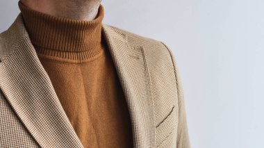 Erkeklerin üstünlük taslayışı, şık erkek kahverengi kazağı ve açık bej ceket. Seçici odak.