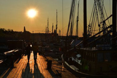 Limanda yelkenlilerle Gün batımında İskelede Yürüyen Çiftin Silueti