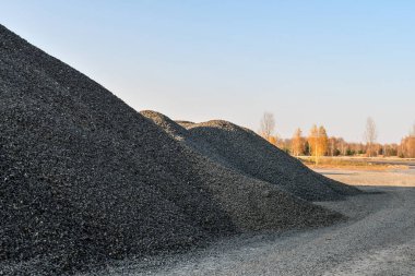 Mavi gökyüzünün arka planında granit bir taş ocağında çakıl yığınları, endüstriyel arka plan