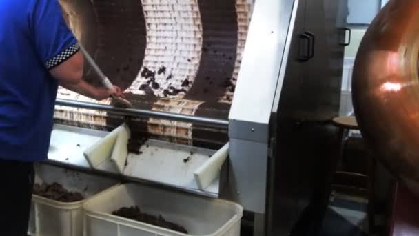 Работник удаляет шоколад из энробатической машины — стоковое видео