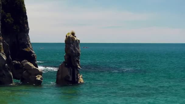 Kayakers paddle past a rock formation — Stock Video