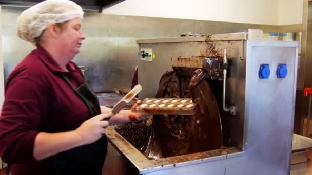 Trabalhador aplica um revestimento de chocolate aos chocolates — Vídeo de Stock