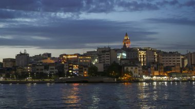 İstanbul 'daki Galata Kulesi ve rıhtımının geniş açılı gece görüntüsü.