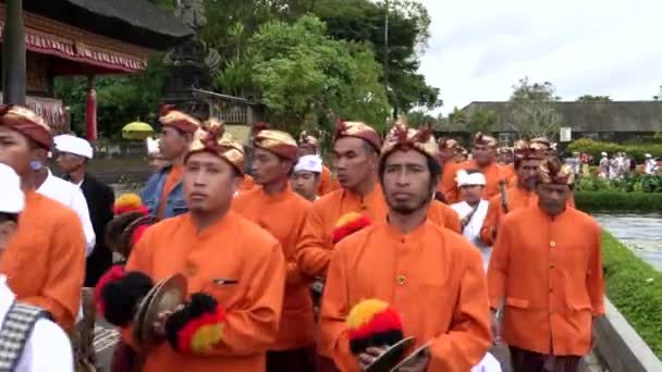 BEDUGUL, INDONESIA MARZO, 15 de marzo de 2018: músicos vestidos de naranja en un desfile en pura danu bratan temple in bali — Vídeo de stock