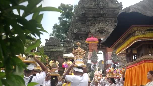UBUD, INDONESIA - MAART, 14, 2018: achteraanzicht van hindoeïstische toegewijden, met offers op hun hoofd, wachtend om een tempel in ubud binnen te gaan op het eiland bali — Stockvideo