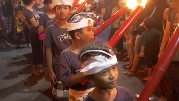 KUTA, INDONESIEN - 16. MÄRZ 2018: Jungen mit brennenden Fackeln warten beim Neujahrsumzug auf dem Bali — Stockvideo