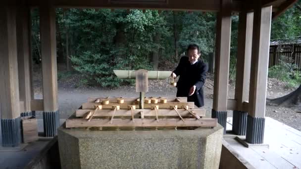 TOKYO, JAPAN - APRIL, 10, 2018: een man met behulp van een water fontein op meiji heiligdom in tokyo — Stockvideo