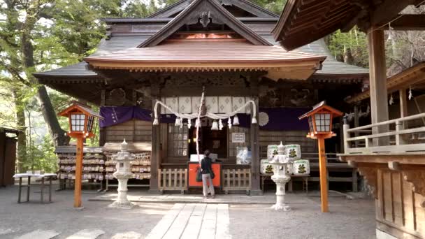 Japoński czciciel ciągnie linę, aby zadzwonić dzwonkiem w świątyni sengen Arakura — Wideo stockowe