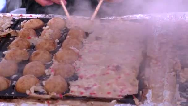 Gros plan d'un cuisinier tournant takoyaki, boules de poulpe, dans une stalle à l'extérieur du sanctuaire kyoto fushimi inari — Video