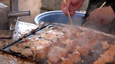 Kyoto 'da bir tezgahta takoyaki yapan bir şefin geniş açılı görüntüsü.