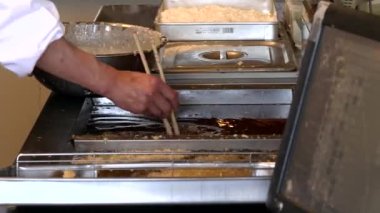 Tempura şefi bir restoranda çiğ karidesleri fritöze koyar.