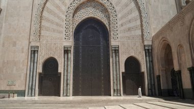 Müslüman bir adam Casablanca 'daki Hassan ii Camii' nin büyük kapısının önünden geçiyor.