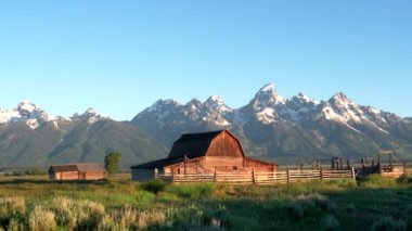 Grand Teton Ulusal Parkı 'ndaki Mormon Sokağı' ndaki bir ahır ve Grand Teton Dağı 'nın gündoğumu görüntüsü.