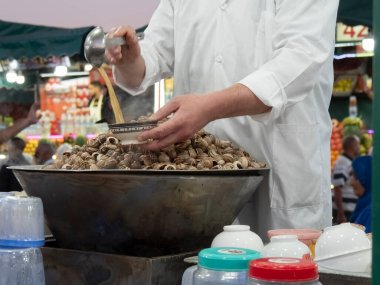Marakeş 'in jemaa el-fnaa pazarında bir açık hava restoranında salyangoz servis ediyorum.