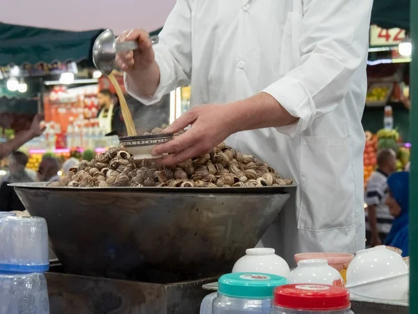 Marakeş 'in jemaa el-fnaa pazarında bir açık hava restoranında salyangoz servis ediyorum.