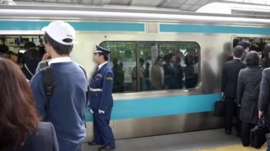 TOKYO, JAPONYAN - APRIL, 18, 2018: Tokyo 'daki bir tren istasyonunda bekçi ve yolcular