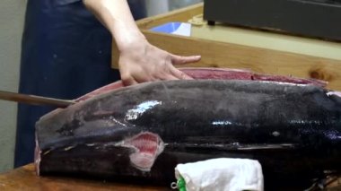 Tokyo 'daki Tsukiji balık pazarında bir ton balığını kesen bir işçiye yakın çekim.
