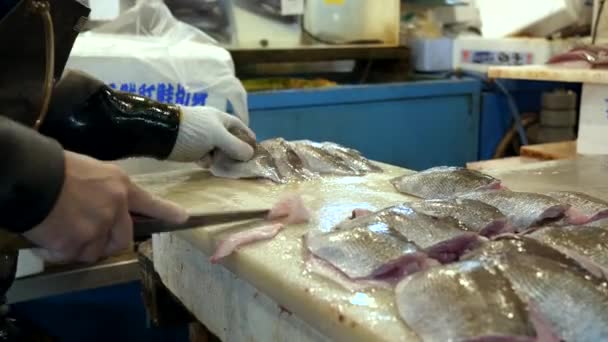 ТОКИО, Япония - 19 апреля 2018 года: рабочий подстригает филе рыбы на рынке Цукидзи в Токё — стоковое видео